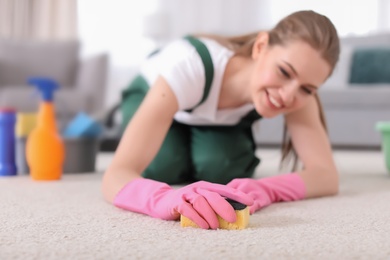 Female worker cleaning carpet at home