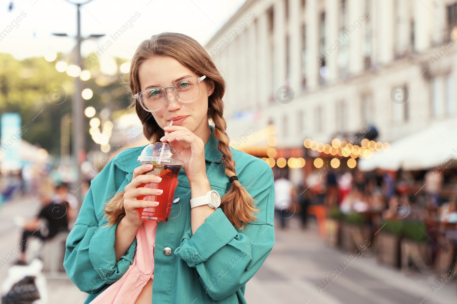 Photo of Young woman with refreshing drink on city street. Space for text