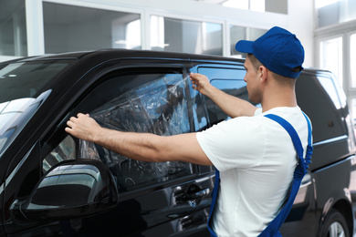 Photo of Worker tinting car window with foil in workshop