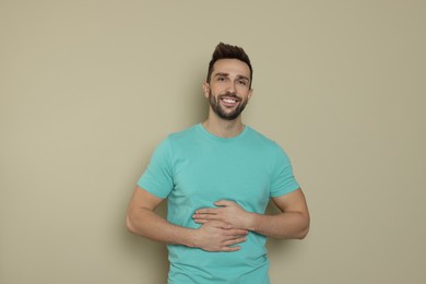 Photo of Happy man touching his belly on beige background. Concept of healthy stomach
