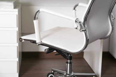 Photo of Comfortable rolling chair near table in modern office