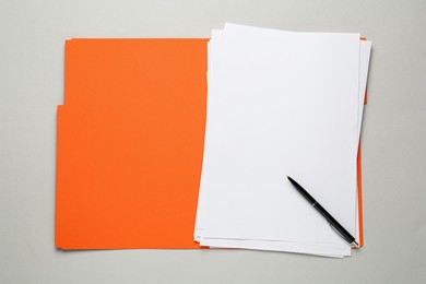 Orange file with blank sheets of paper and pen on light grey background, top view. Space for design