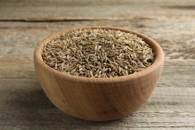 Bowl of caraway seeds on wooden table, closeup