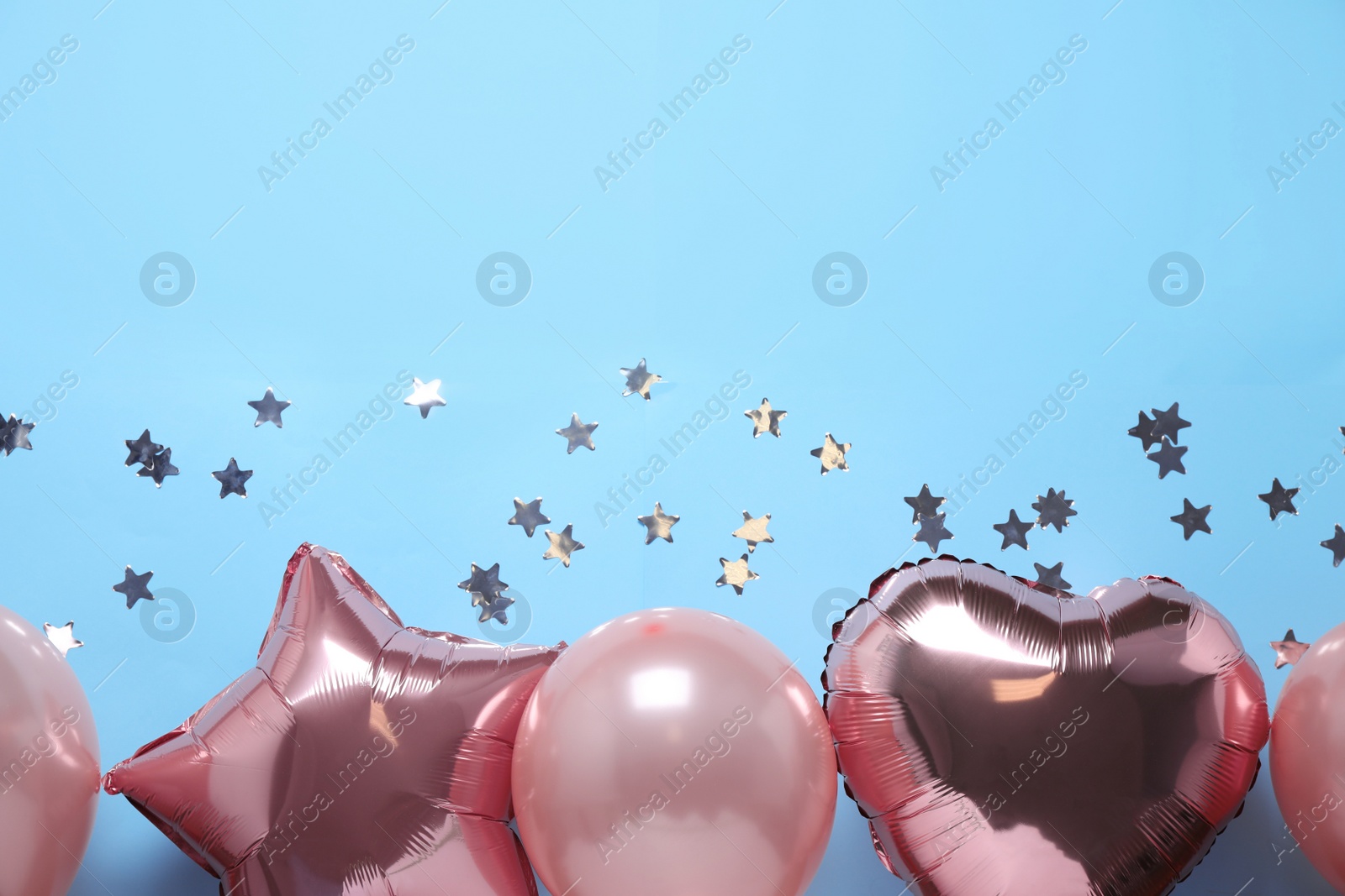 Photo of Colorful balloons and confetti on light blue background, flat lay. Space for text