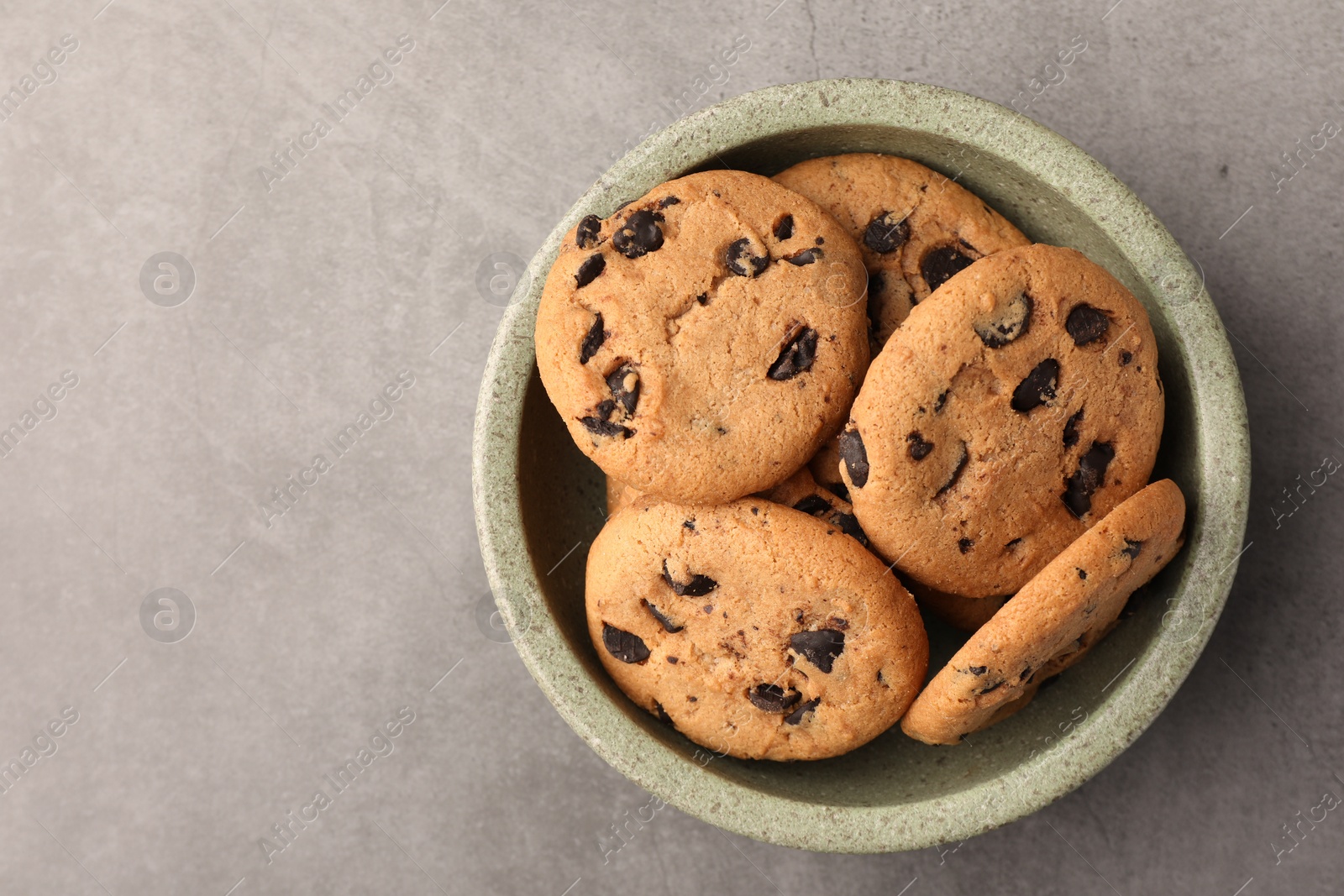 Photo of Delicious chocolate chip cookies on grey table, top view. Space for text