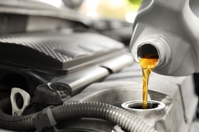 Photo of Pouring oil into car engine, closeup