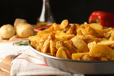 Photo of Dish of delicious oven baked potatoes on table, closeup