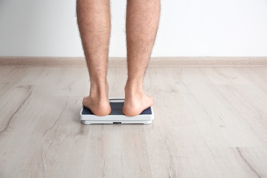 Overweight man measuring his weight indoors