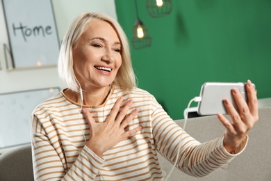 Mature woman using video chat on mobile phone at home