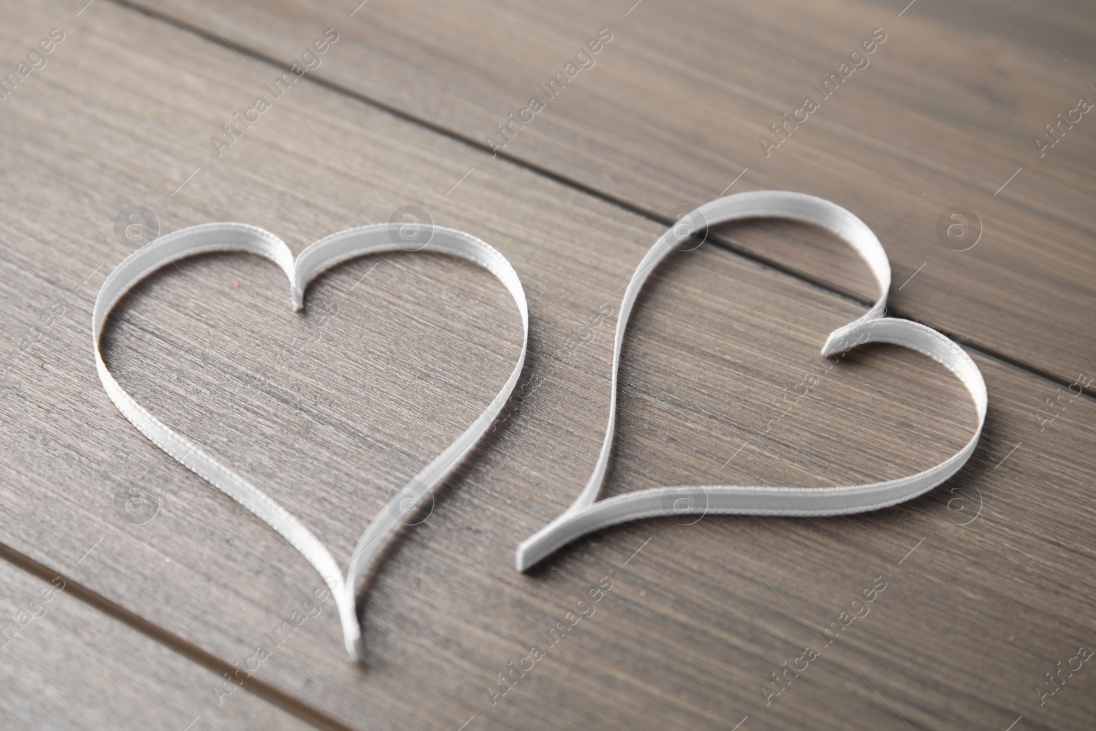 Photo of Hearts made of white ribbon on wooden background. Valentine's day celebration