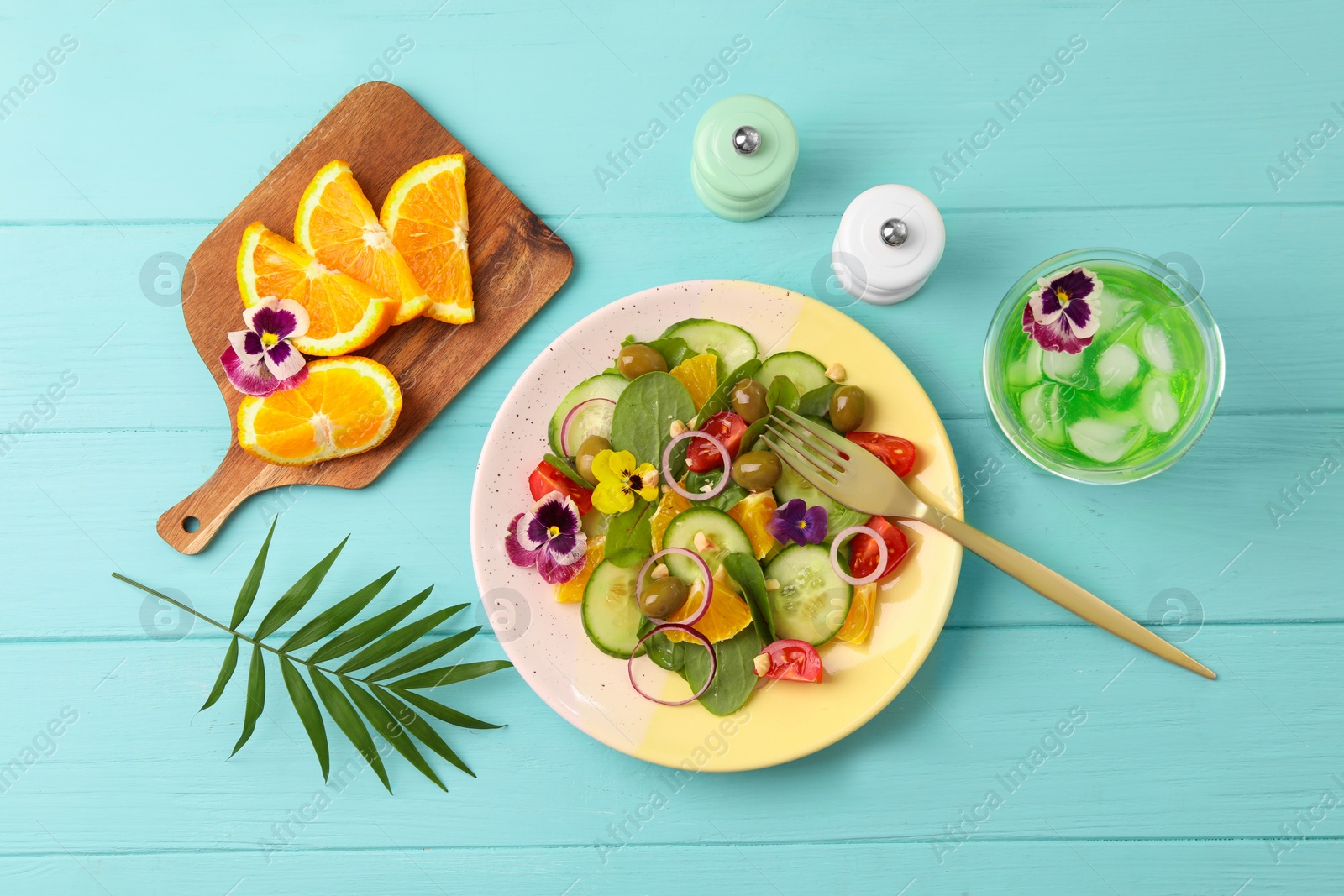 Photo of Delicious salad with orange, spinach, olives and vegetables served on turquoise wooden table, flat lay