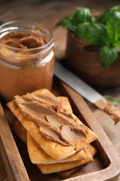 Photo of Crispy crackers with delicious meat pate on wooden table, closeup