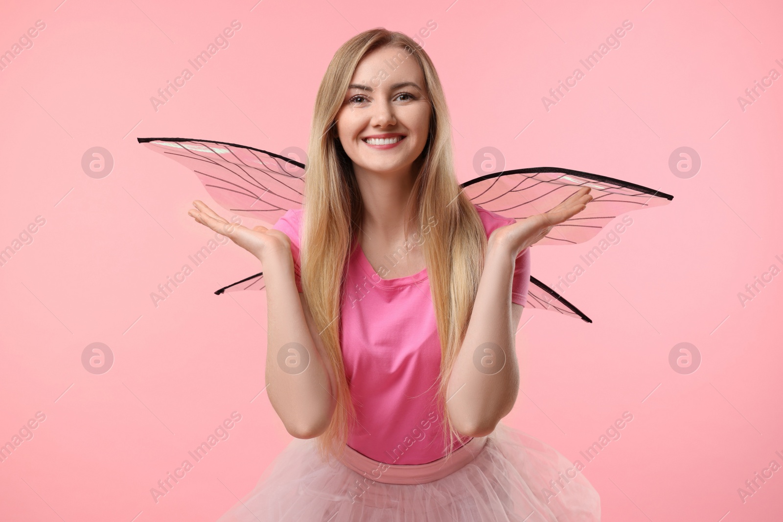 Photo of Beautiful girl in fairy costume with wings on pink background