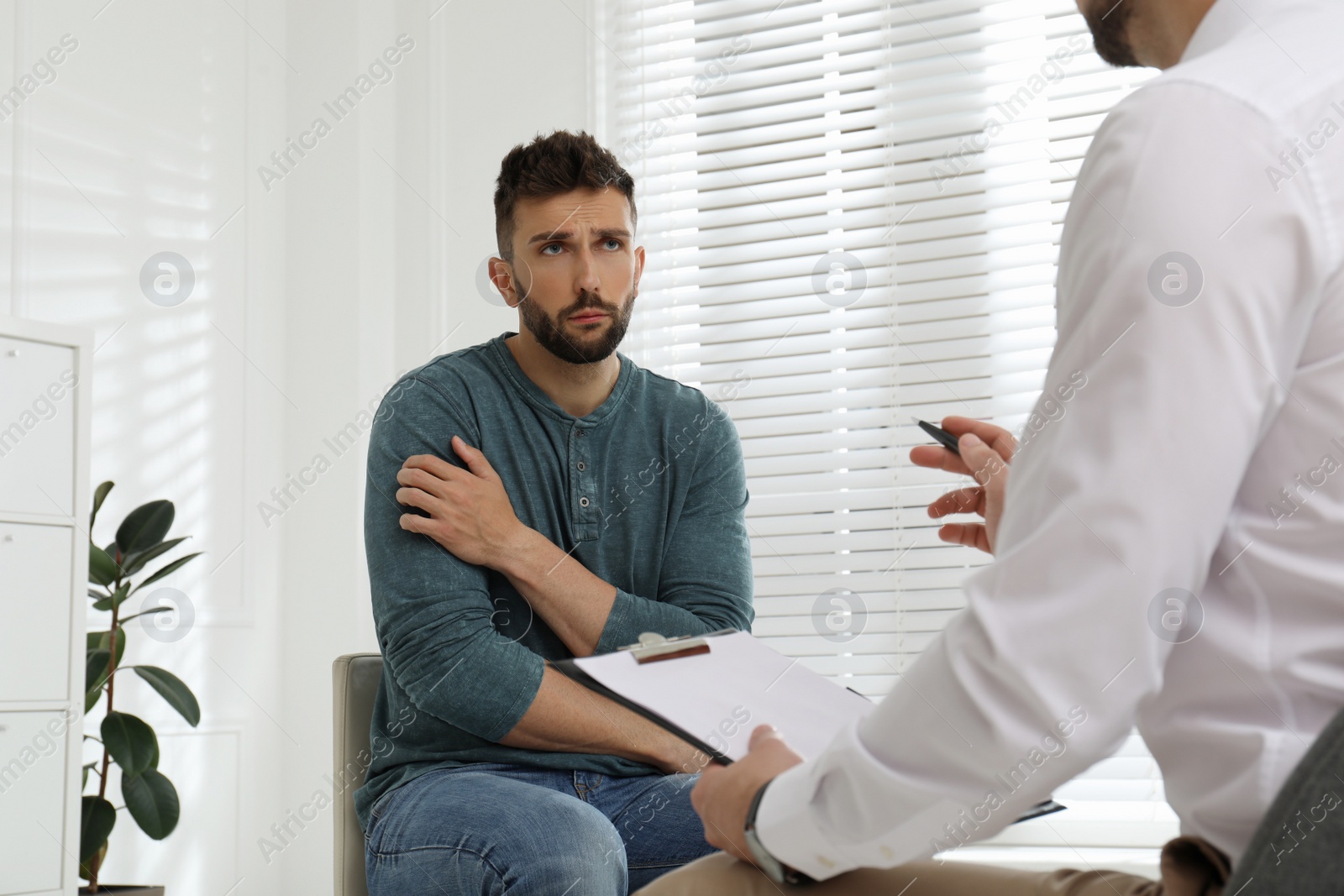 Photo of Psychotherapist working with drug addicted man indoors