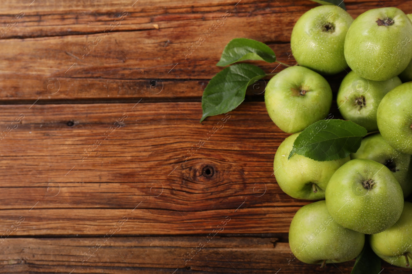 Photo of Fresh ripe green apples with water drops on wooden table, flat lay. Space for text