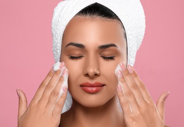 Photo of Beautiful woman applying facial cleansing foam on pink background