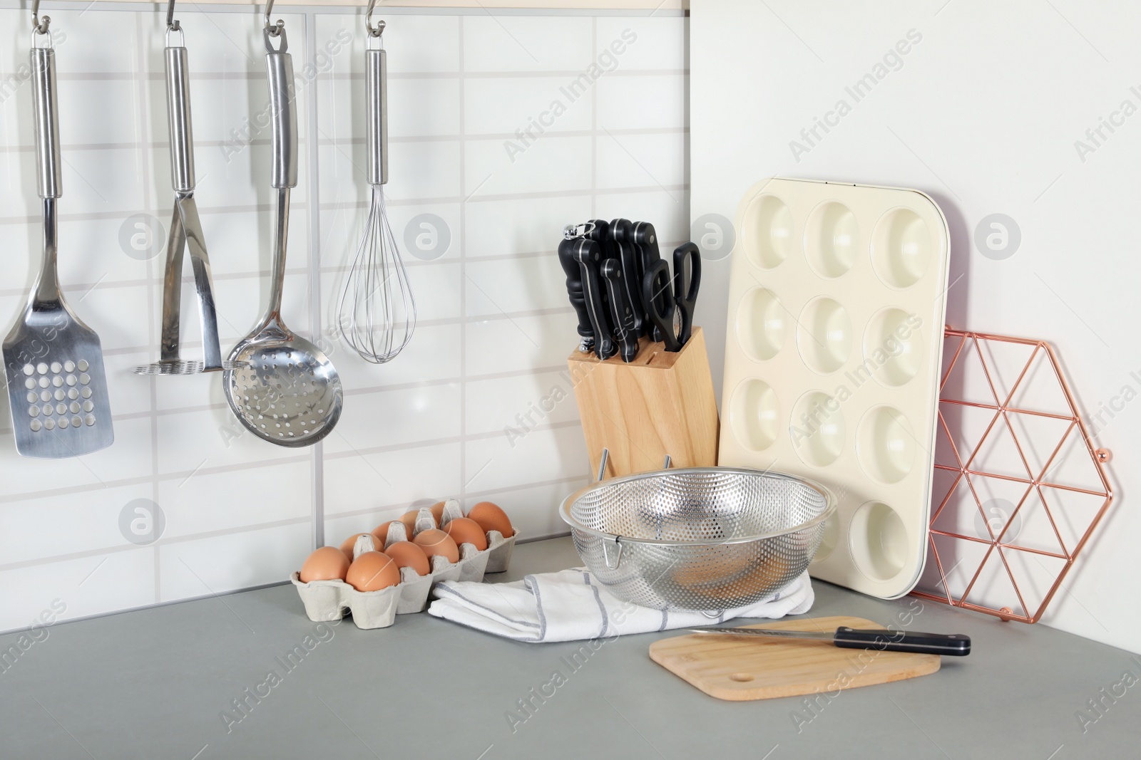 Photo of Set of clean cookware, utensils and eggs on table in modern kitchen