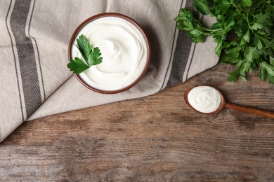 Photo of Flat lay composition with sour cream and parsley on wooden table, space for text