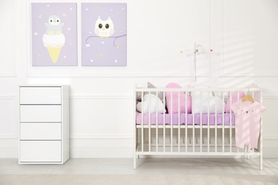 Crib and dresser near wall with pictures in cozy baby room. Interior design