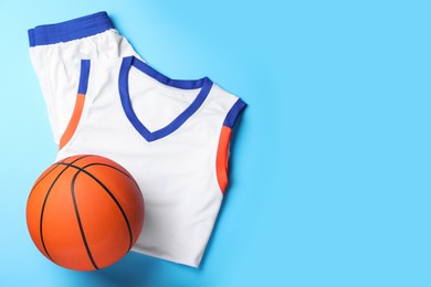 Photo of Basketball uniform and ball on light blue background, flat lay. Space for text
