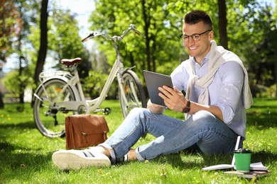 Man working with tablet on grass in park