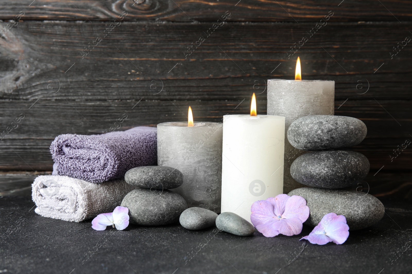 Photo of Composition with zen stones, towels and candles on table against wooden background