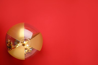 Photo of Bright beach ball on red background, top view. Space for text