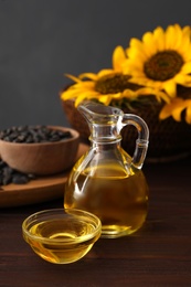 Photo of Sunflower oil in glass bowl and jug on wooden table