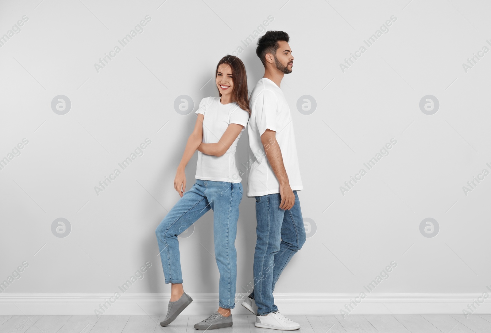 Photo of Young couple in stylish jeans near light wall