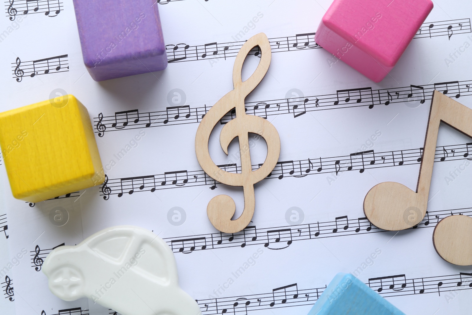 Photo of Wooden notes and toys on music sheet, flat lay. Baby song concept