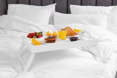 Photo of White tray with delicious breakfast on bed