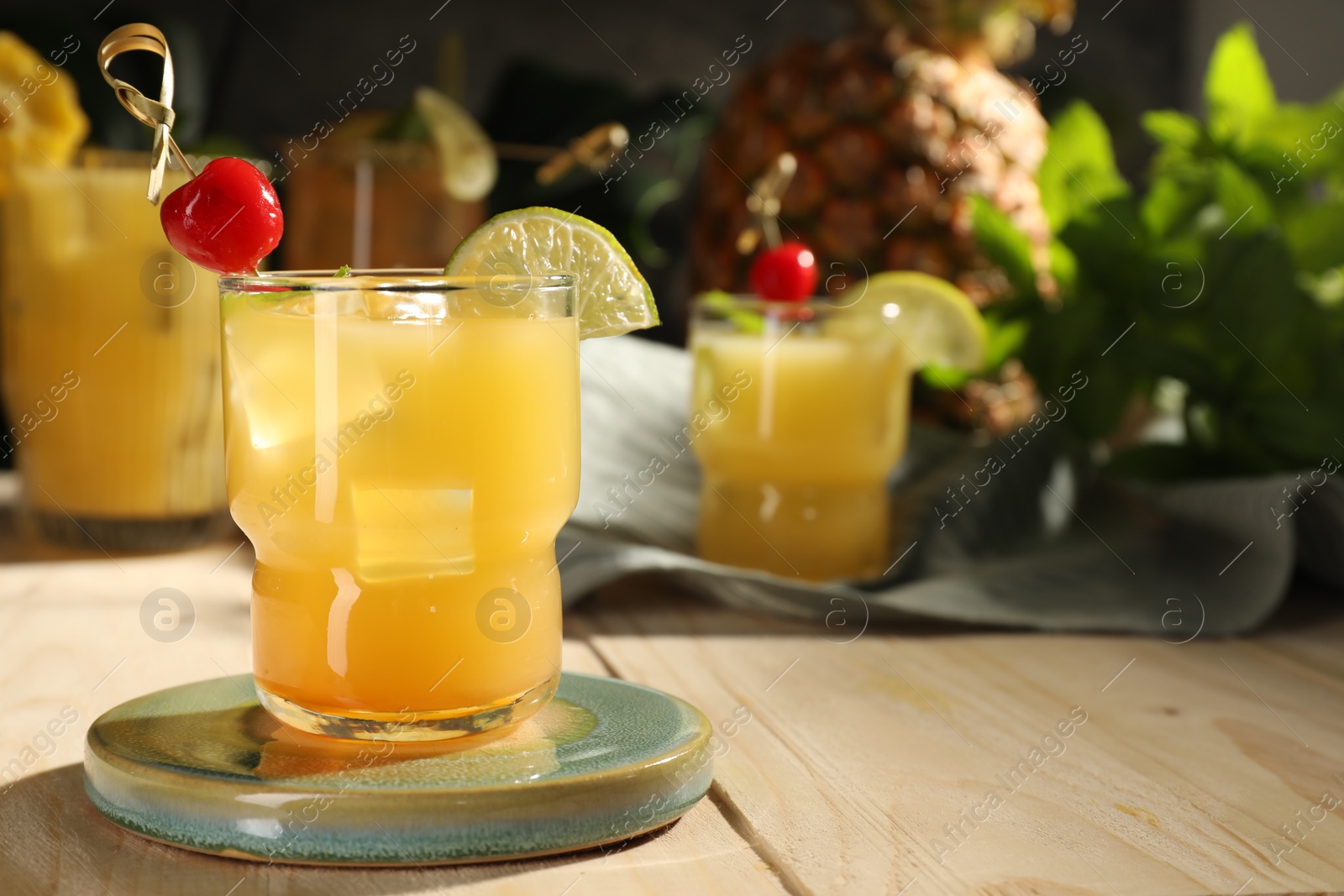 Photo of Tasty pineapple cocktail with cherry and lime on wooden table. Space for text