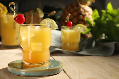Photo of Tasty pineapple cocktail with cherry and lime on wooden table. Space for text