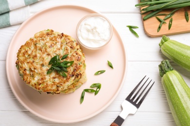 Photo of Delicious zucchini fritters served on white wooden table, flat lay