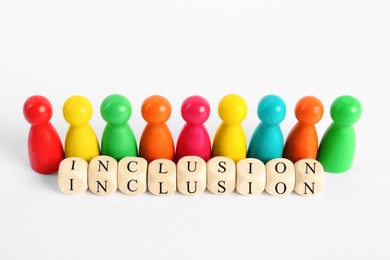 Colorful pawns and wooden cubes with word Inclusion on white background