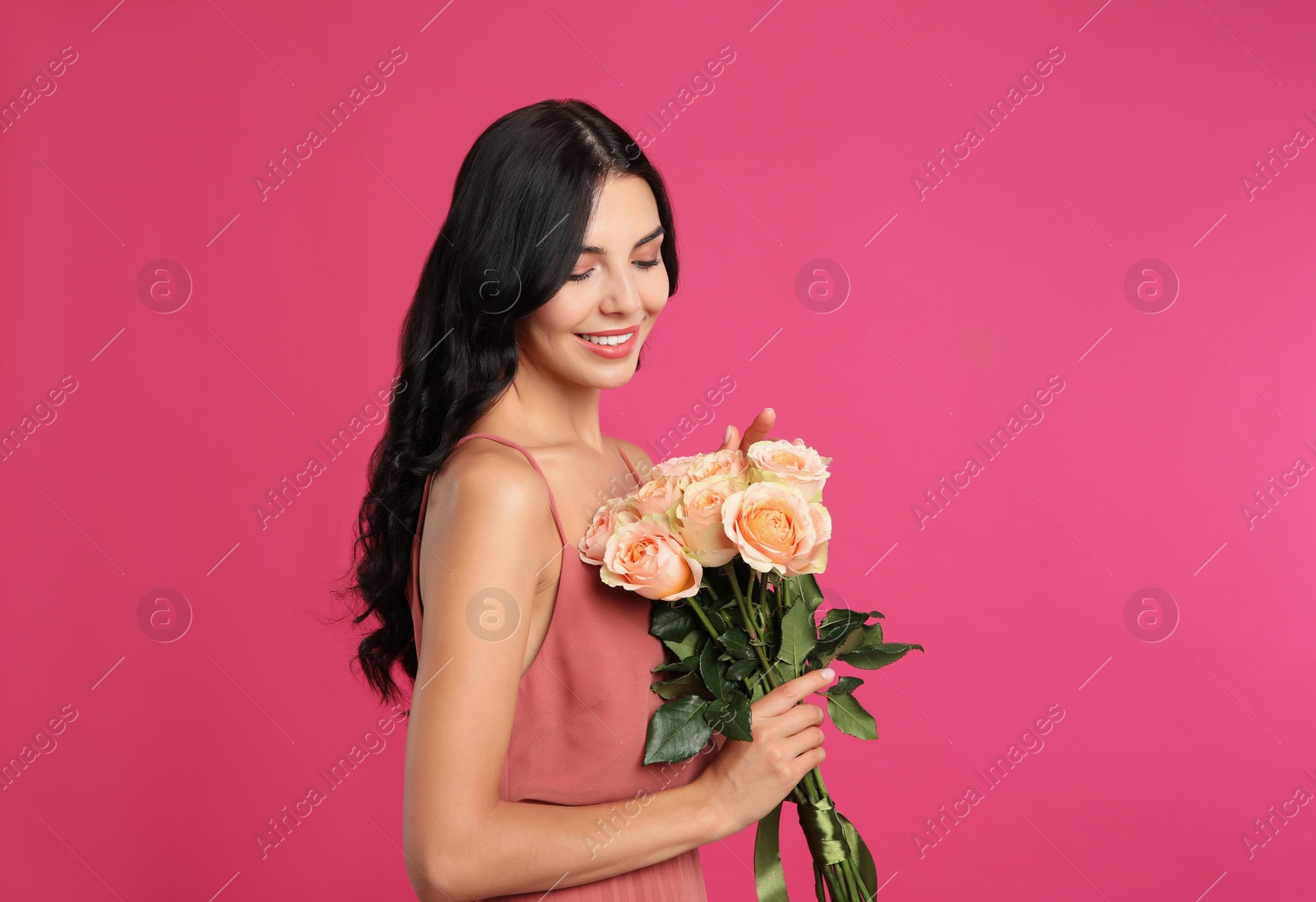 Photo of Portrait of smiling woman with beautiful bouquet on pink background