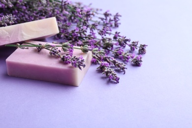 Hand made soap bars with lavender flowers on violet background, space for text