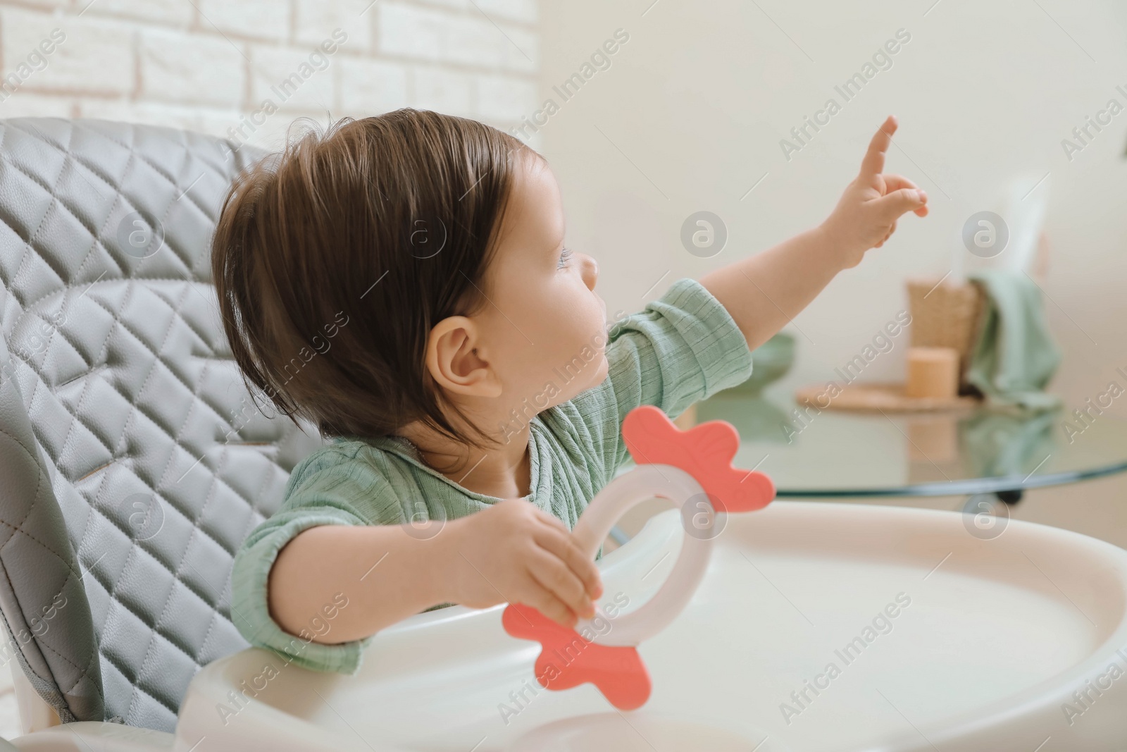 Photo of Cute little baby with teether in high chair indoors