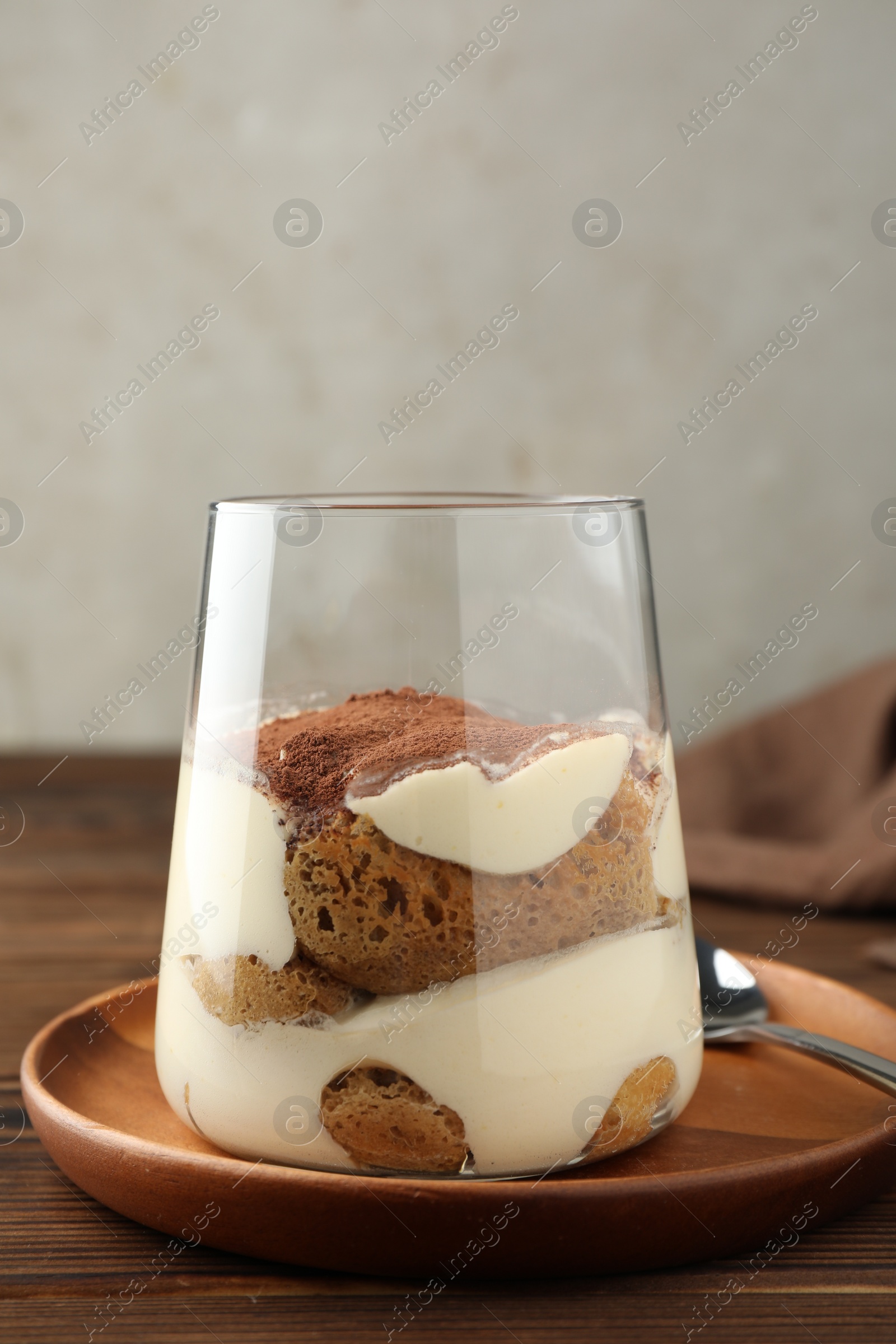 Photo of Delicious tiramisu in glass on wooden table, closeup