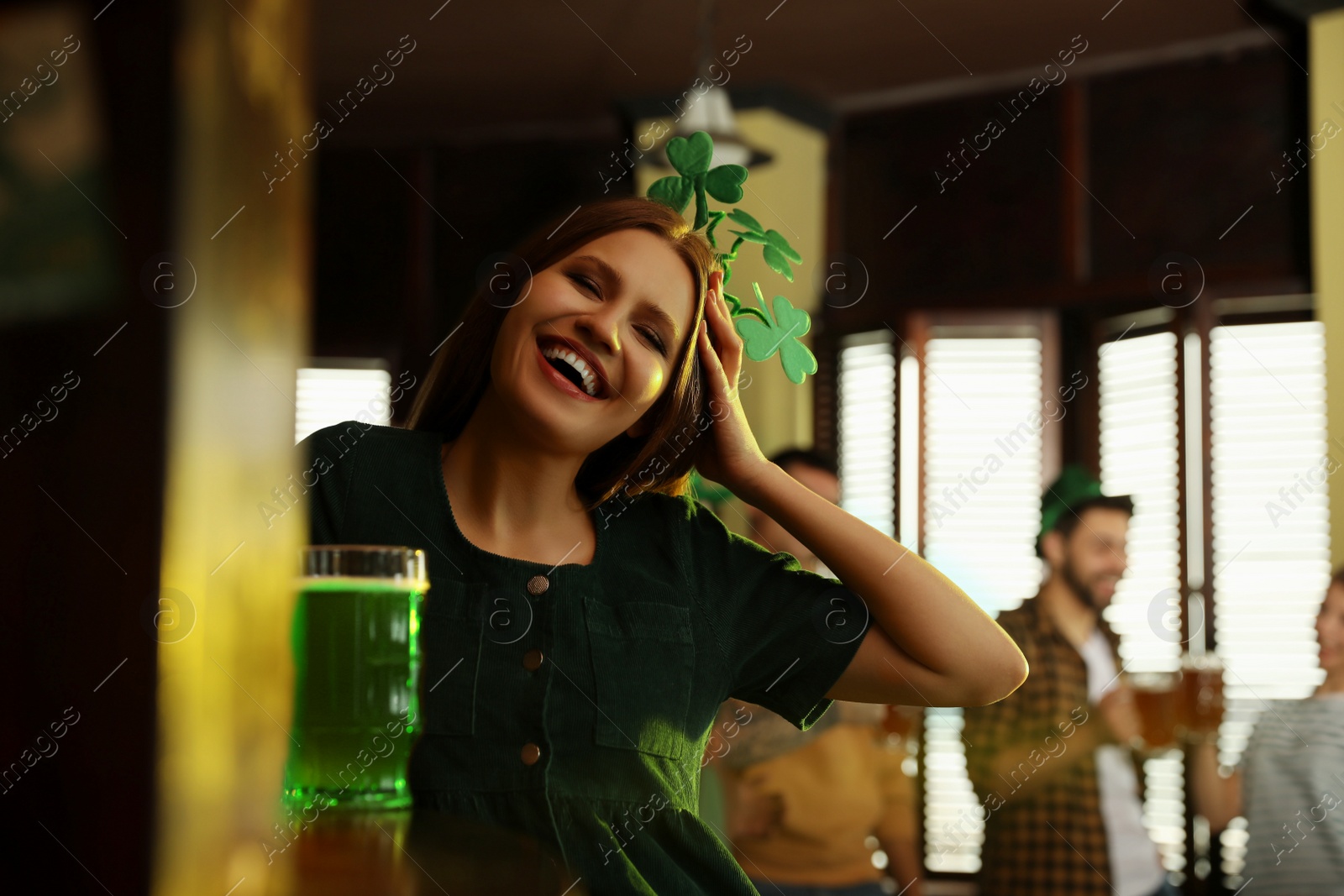 Photo of Young woman with glass of green beer in pub. St. Patrick's Day celebration