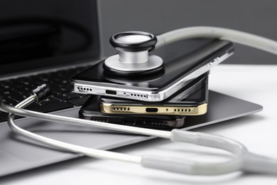 Photo of Stack of electronic devices and stethoscope on white table