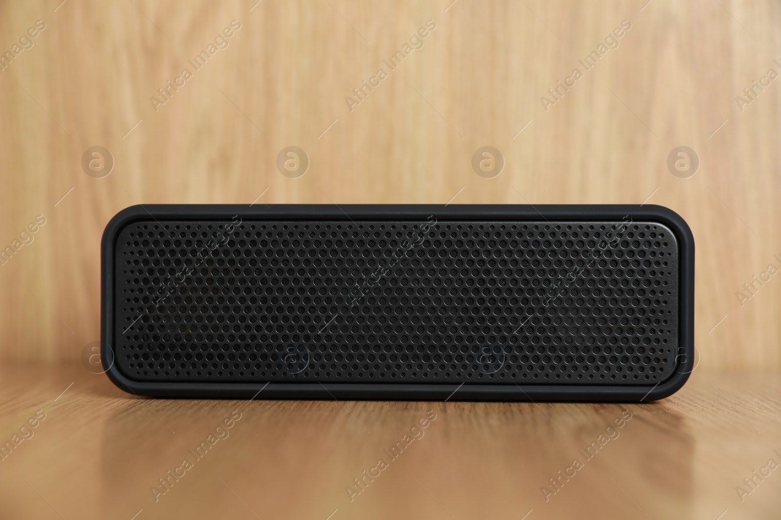Photo of One black portable bluetooth speaker on wooden table. Audio equipment