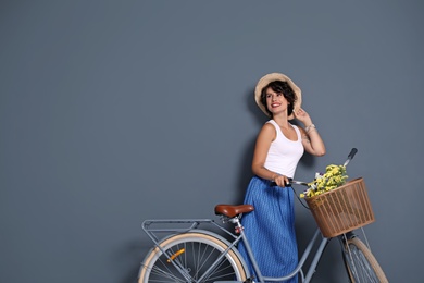 Portrait of beautiful young woman with bicycle on color background