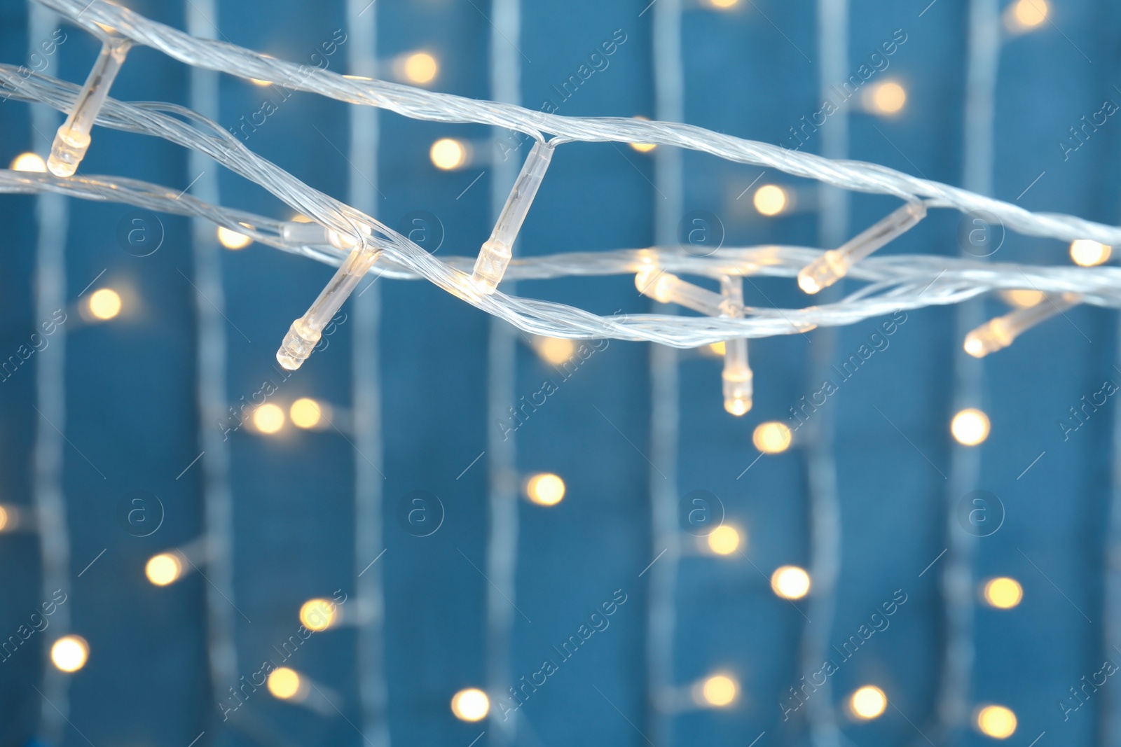 Photo of Beautiful Christmas lights on color background, closeup