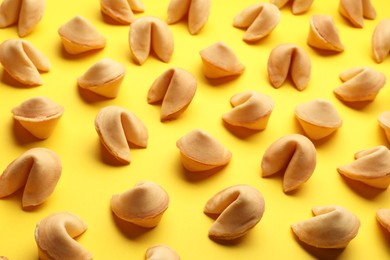 Photo of Many tasty fortune cookies with predictions on yellow background
