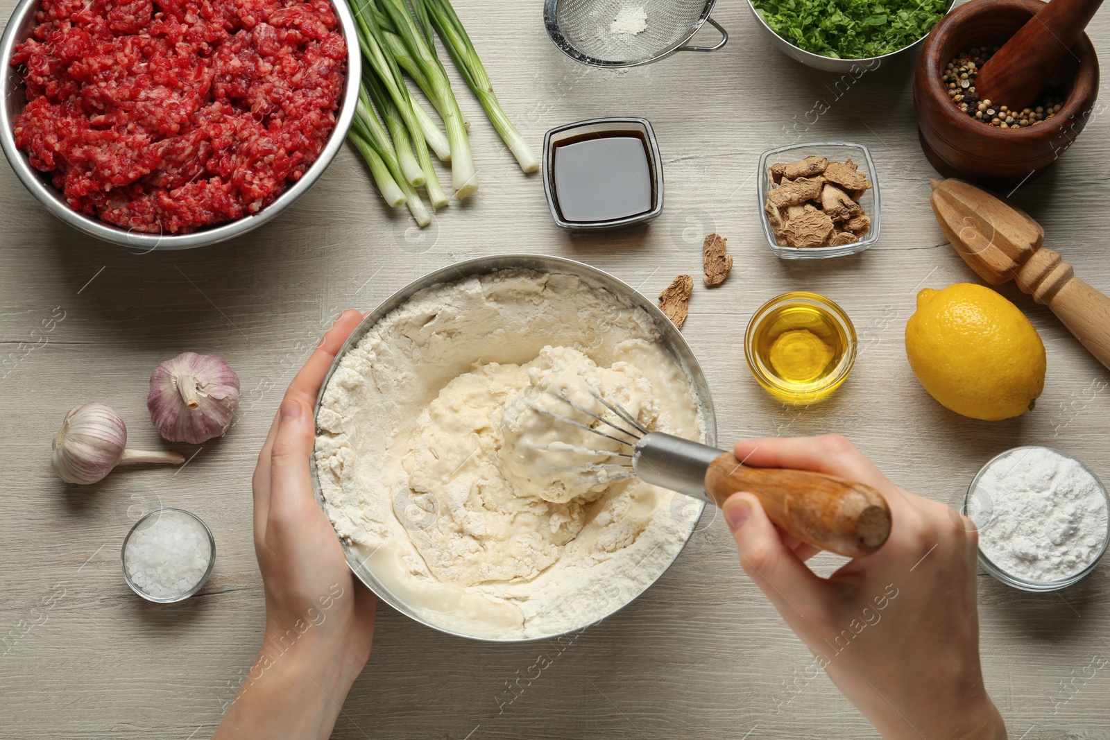 Photo of Woman cooking delicious gyoza at white wooden table, top view