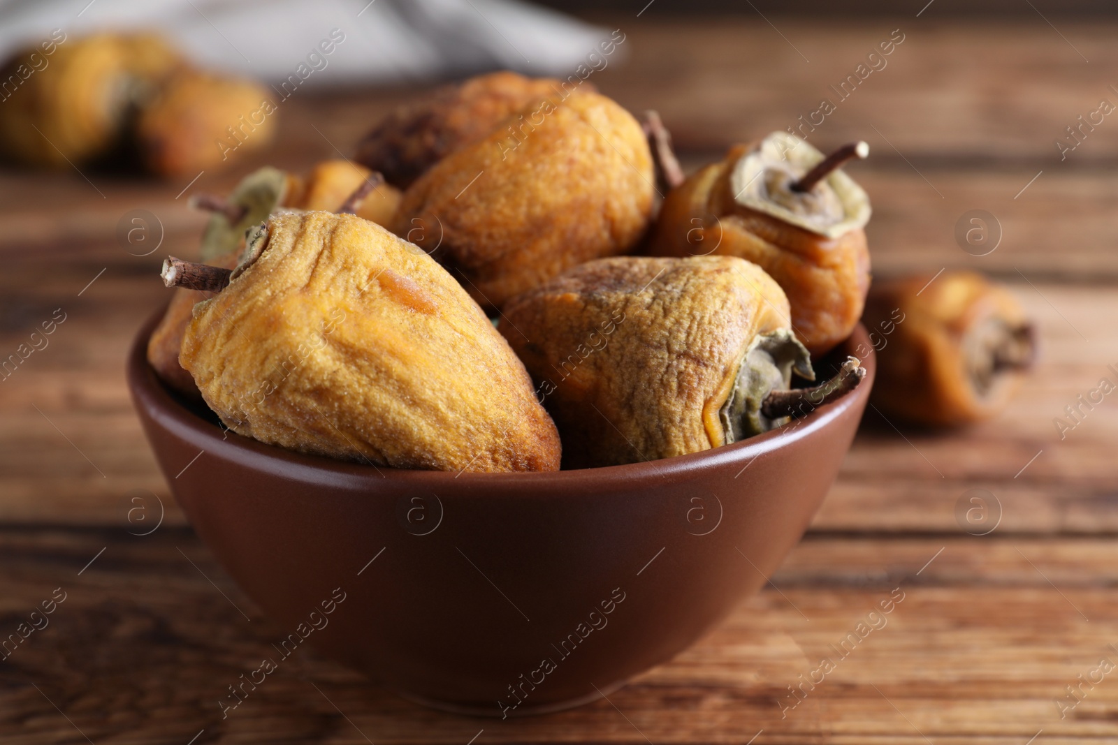 Photo of Bowl with tasty dried persimmon fruits on wooden table