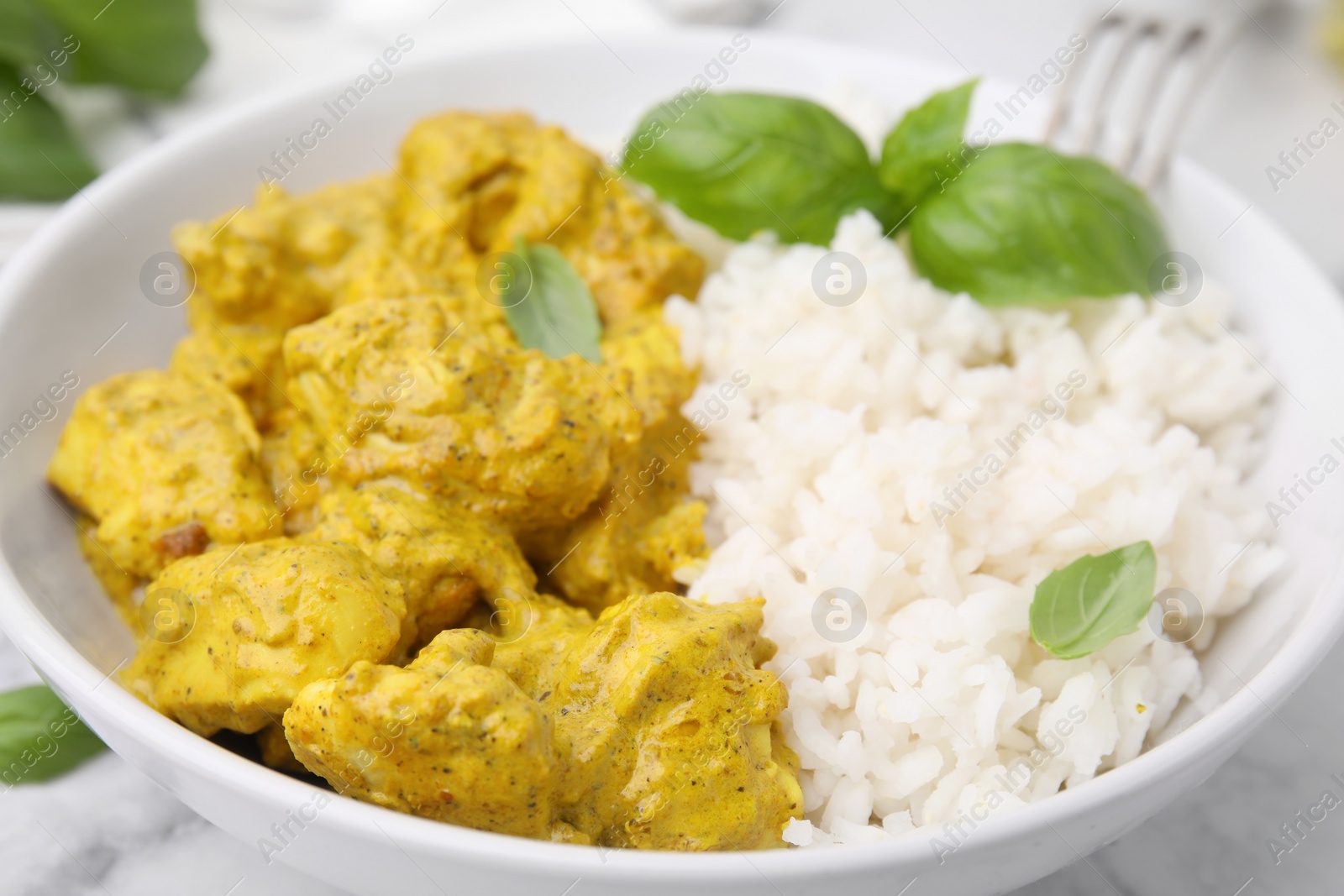 Photo of Delicious rice and chicken with curry sauce in bowl, closeup