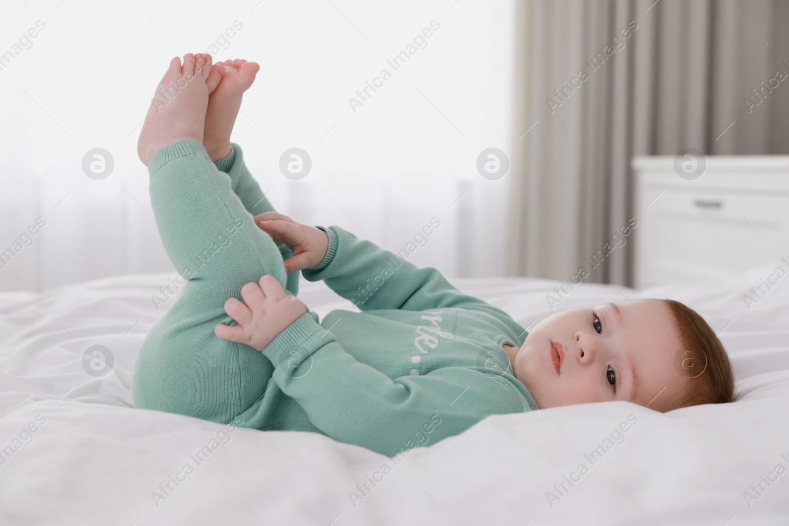 Photo of Cute little baby lying on bed with soft blanket indoors