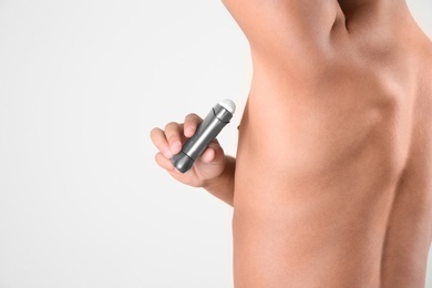 Photo of Young man using deodorant on white background, closeup. Space for text